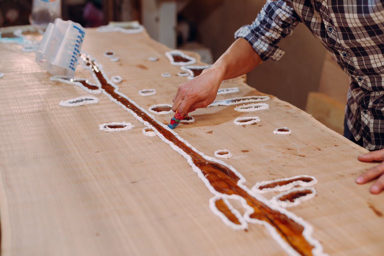 home-img A skilled craftsman applying resin on a wooden table in a workshop setting.